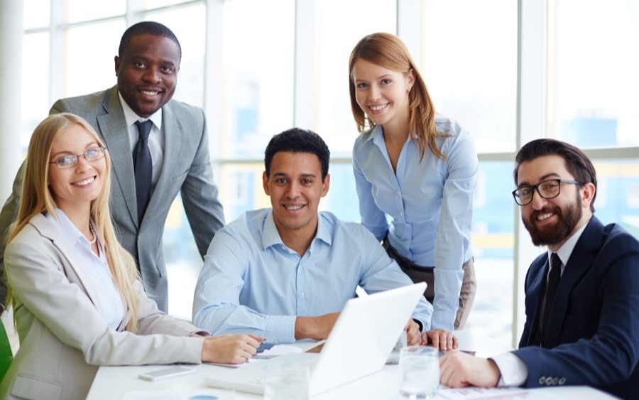 A consulting team meeting around a laptop in a bright office